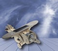 Wooden toy airplane with solar panel on blue wood, on blue sky and cloud background Royalty Free Stock Photo