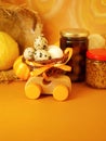 Wooden toy car with a basket of quail eggs on a bright yellow background painted in pastels, pumpkins