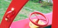 Wooden toy car in the playground for children. Red metal steering wheel of children`s wooden car on the playground Royalty Free Stock Photo