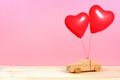 Wooden car with red heart balloons against pink background Royalty Free Stock Photo