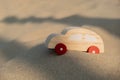 Wooden toy car on sandy beach background. Eco-friendly travel, reduce carbon footprints, environmental impact, Conscious