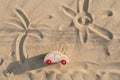 Wooden toy car on sandy beach background with painted sun and palm. Eco-friendly travel, reduce carbon footprints