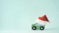 The wooden toy car and Santa Claus hat on snow and mint color background Royalty Free Stock Photo