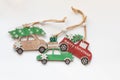 Wooden toy cars are carrying New Year's gifts and a Christmas tree on the roof on a white background