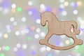 Wooden toy in the form of a rocking horse against a background of bokeh from Christmas garlands. Horizontal photo, soft focus, Royalty Free Stock Photo