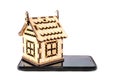 Wooden, toy house on a black phone on a white background, side view. Royalty Free Stock Photo