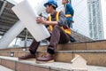 Wooden toy house on constructor team sitting with layout paper and survey on construction site Royalty Free Stock Photo