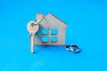 Wooden toy house with wedding rings and keys on a blue background. concept of moving a young family to new home Royalty Free Stock Photo