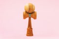 Wooden toy Kendama with blue thread on a pink background