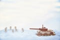 A wooden toy tank and little men in the snow. Russia and Ukraine are at war in winter. Encirclement, retreat, attack Royalty Free Stock Photo