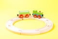 Wooden toy train set on tracks on yellow background. Royalty Free Stock Photo