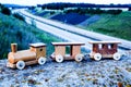 Wooden toy train on wall above a freeway