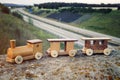 Wooden toy train on wall above a freeway