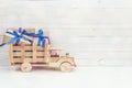 Wooden toy truck with gift boxes in the back on a white wooden b Royalty Free Stock Photo