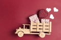 Wooden toy truck with gift boxes and hearts in the back on a red background. Place for text Royalty Free Stock Photo