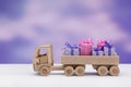 Wooden toy truck with gifts in boxes decorated with ribbons and bows in elegant paper.