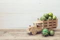 Wooden toy truck with a green Christmas balls in the back on white wooden background. Place for text Royalty Free Stock Photo