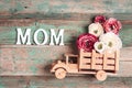 Wooden toy truck with peonies flowers in the back and word MOM on wooden turquoise boards. Space for text Royalty Free Stock Photo