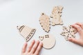 Wooden toys in kid hands, ready to make Christmas decorations.Wooden Christmas tree ornaments on white background.Home Royalty Free Stock Photo