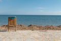 Wooden trash can with a bag on the boulevard of a public city beach on the background of garbage and clear blue sea and sky