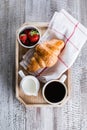 Wooden tray with cup of coffee, freshly baked croissants and fresh strawberry. Breakfast concept Royalty Free Stock Photo