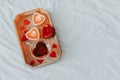 Wooden tray with cup of hot morning tea, burning candle on white bed linen. Happy Valentines Day. Copy space Royalty Free Stock Photo