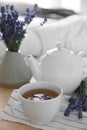 Wooden tray with cup of hot tea and lavender flowers on bed, closeup. Tasty breakfast