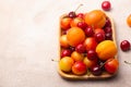 Wooden tray with fresh cherries, plums and apricots with water drops Royalty Free Stock Photo