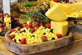 A beautiful wooden tray with sliced cheese decorated with strawberries, black grapes and rosemary on the table Royalty Free Stock Photo