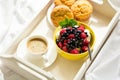 Wooden tray with tasty breakfast on bed. Espresso, banana muffins, cottage cheese with blueberry and raspberry Royalty Free Stock Photo