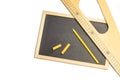 Wooden triangle ruler, a yellow pencil and chalks on a blackboard and on a white background Royalty Free Stock Photo