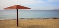 Wooden umbrella on an empty sandy beach. Blue sky and calm sea background. Royalty Free Stock Photo