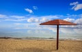 Wooden umbrella on an empty sandy beach. Blue sky and calm sea background. Royalty Free Stock Photo