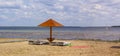 Wooden umbrella and sunbeds or beach lounger on the empty beach by the lake Royalty Free Stock Photo