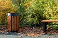 A wooden urn and a comfortable empty park bench. A cozy place to relax for a walk.