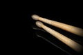 Wooden used drumsticks on a black background with reflections