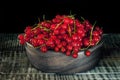 Wooden utensils with ripe red currant berries on a dark background.