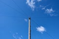 Wooden utility pole and wires against bright blue sky with white clouds. Royalty Free Stock Photo