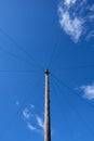 Wooden utility pole and wires against bright blue sky with white clouds. Royalty Free Stock Photo