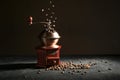 Wooden vintage coffee grinder on a slate plate, falling and lying roasted beans against a dark background with copy space Royalty Free Stock Photo