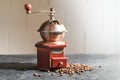 Wooden vintage coffee grinder and some roasted beans on a slate kitchen counter against a bright wall, copy space Royalty Free Stock Photo