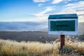 Wooden vintage mailbox in beautiful nature landscape, golden dried grass with small flower and sea of fog and blue sky in the Royalty Free Stock Photo