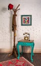 Wooden vintage side table, golden antique telephone, and coat hanger stand with red fez and scarf