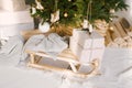 Wooden vintage sleigh with a blanket and gifts under the Christmas tree. Christmas decor in the interior of the house Royalty Free Stock Photo