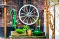 Wooden wagon wheel, water pump on a house wall. Royalty Free Stock Photo