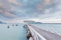 Wooden walk way leading to sea with cloudy sky