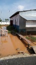 A wooden walk way from a tin sheded room over stagnant rain water in a construction site. Royalty Free Stock Photo