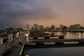 Wooden walkway leading to empty boat docks with fiery evening sky on chilly night