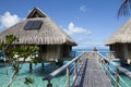 Wooden walkways over the water of the blue tropical sea to authentic traditional Polynesian thatched roof houses with eco-friendly Royalty Free Stock Photo