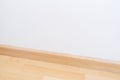 Wooden wall base skirting, finishing material with wood laminate floor and white mortar wall. Empty room with white wall and Royalty Free Stock Photo